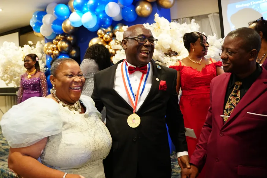 Bishop Donald McFarlane laughs with church members at the NFCM anniversary banquet.
