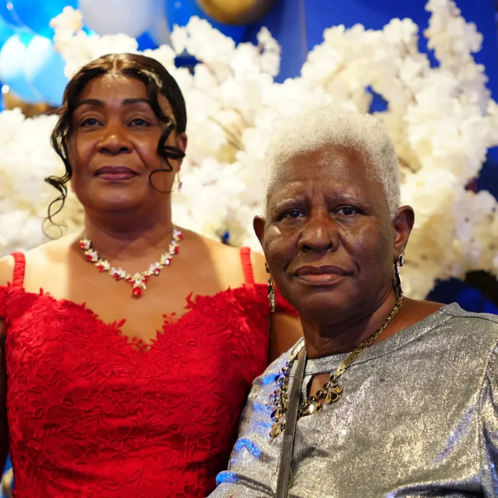 Two women in formal wear smile together at the NFCM anniversary banquet.