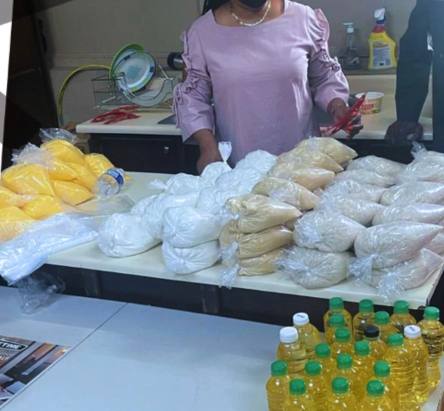 A volunteer packing bags of rice, flour and cornmeal beside bottles of cooking oil