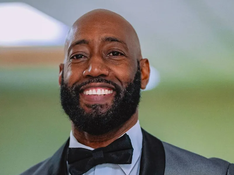 A smiling man in a grey tuxedo and bow tie at the NFCM Prayer Breakfast 2026.