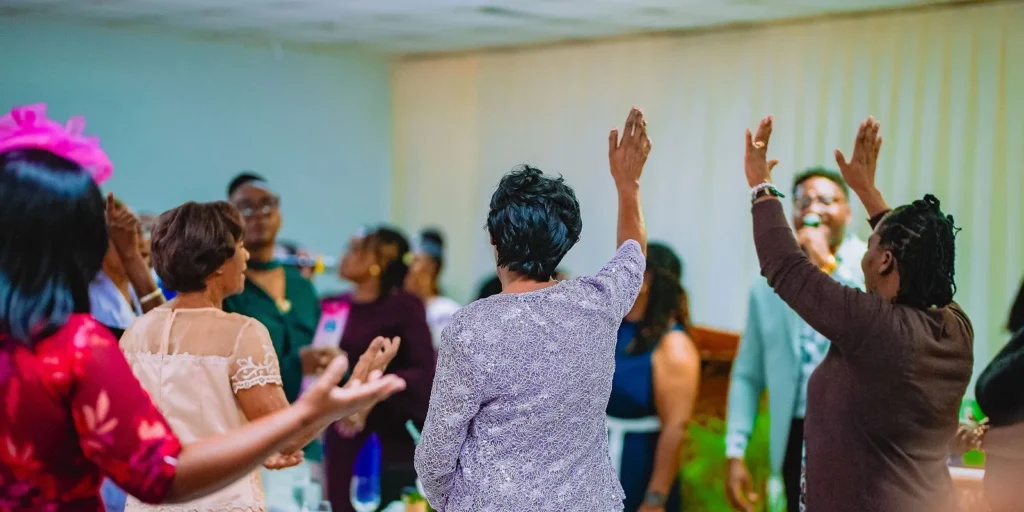 Members stand with hands raised in worship at the NFCM Prayer Breakfast 2026.