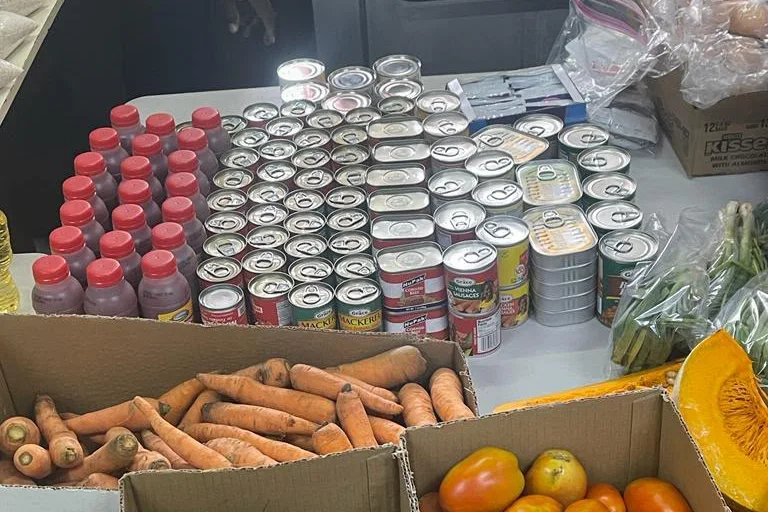 Boxes of carrots, sweet potatoes and tomatoes with canned goods and juice prepared by the NFCM Pantry.