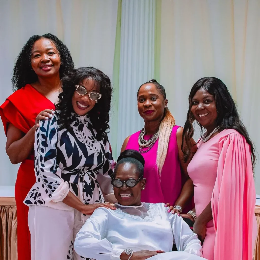 Five women in colourful dresses pose together at the NFCM Prayer Breakfast 2026.