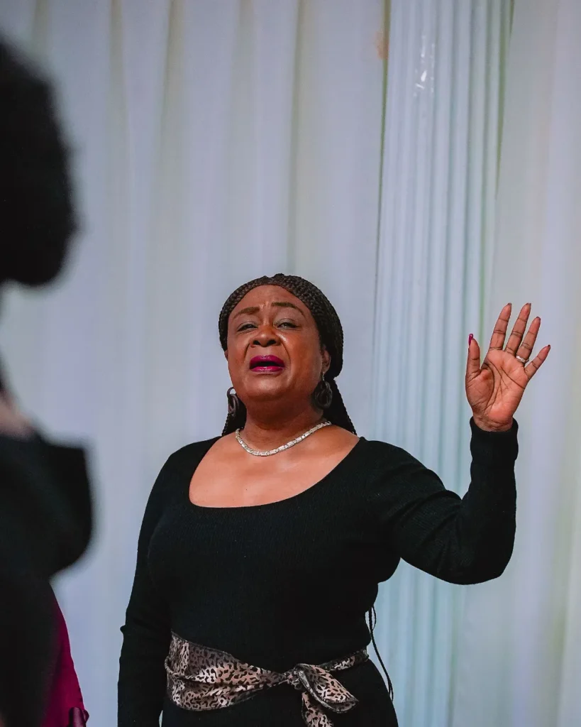 A woman sings with her hand raised in worship at the NFCM Prayer Breakfast 2026.