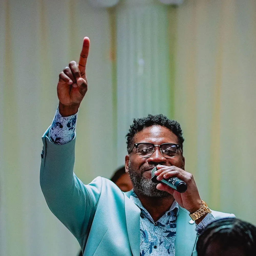 A young worship leader sings and points upward at the NFCM Prayer Breakfast 2026.